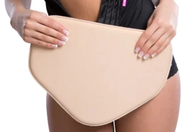 Il cuscino di compressione sagomato tenuto con le mani davanti all'addome