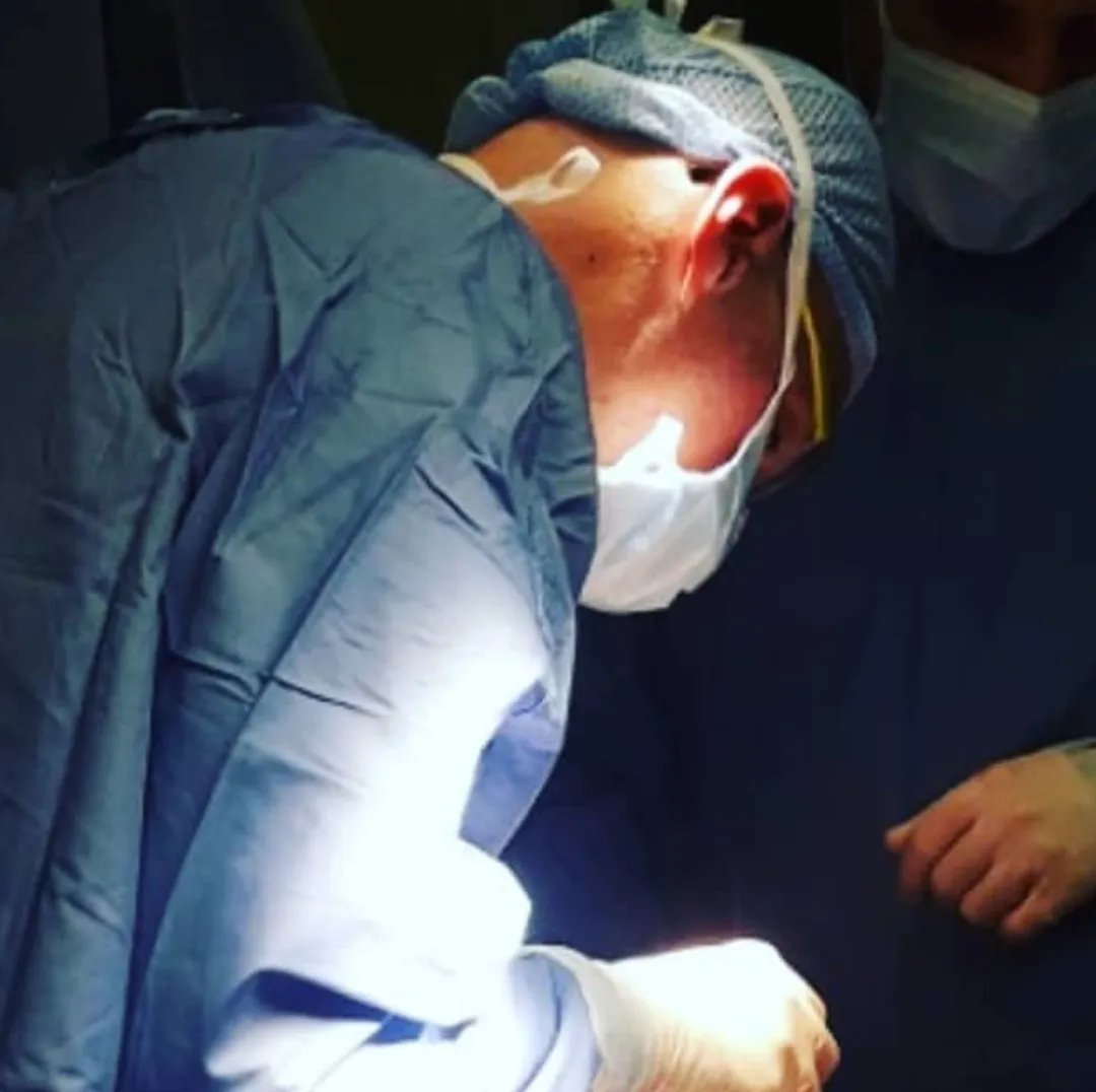 Chirurgo in camice e mascherina chino sul campo operatorio durante un intervento open
